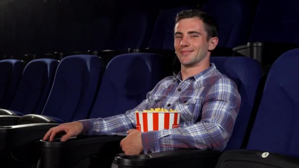 Feliz hombre guapo sonriendo alegremente sentado en el cine — Vídeos de Stock