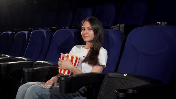 Приваблива молода жінка насолоджується фільмами в кінотеатрі — стокове відео