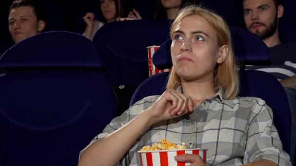 Привлекательная женщина ест попкорн на кинопремьере в кинотеатре — стоковое видео