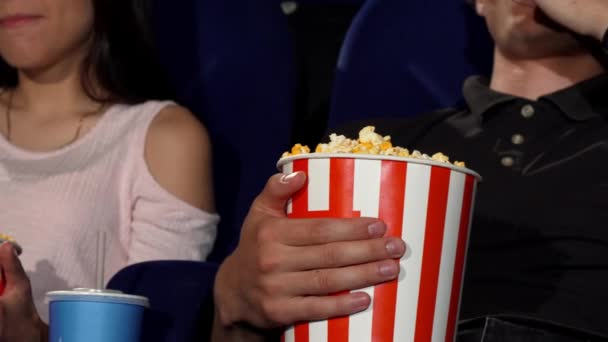 Férfi és nő popcornt eszik a moziban. — Stock videók