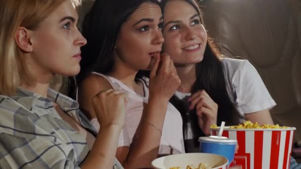 Tres amigas jóvenes riendo mientras ven una película juntas — Vídeo de stock