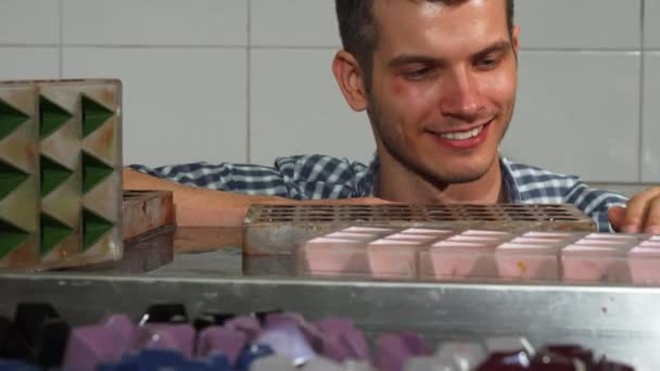 Confeiteiro alegre examinando doces artesanais em sua cozinha — Vídeo de Stock