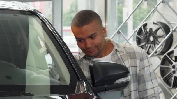 Schöner junger afrikanischer Mann lächelt und hält Autoschlüssel im Autohaus — Stockvideo