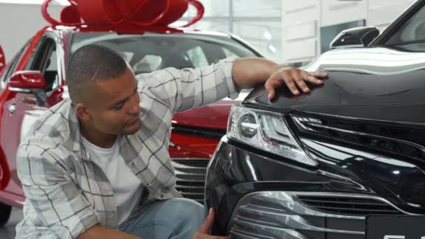 Bonito homem africano mostrando polegares para cima enquanto examina carro novo — Vídeo de Stock