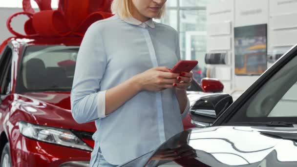 Kobieta za pomocą jej inteligentnego telefonu w salonie dealera samochodów — Wideo stockowe