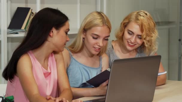 Drei fröhliche Studentinnen, die gemeinsam ein Buch lesen — Stockvideo
