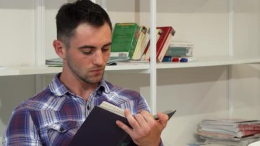 Kitap okurken sevinçle gülümseyen yakışıklı genç