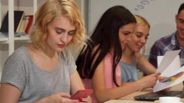 Toplantı sırasında akıllı telefonunu kullanarak genç iş kadını