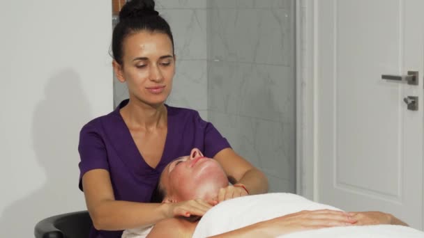 Весела масажистка посміхається під час роботи з клієнтом — стокове відео