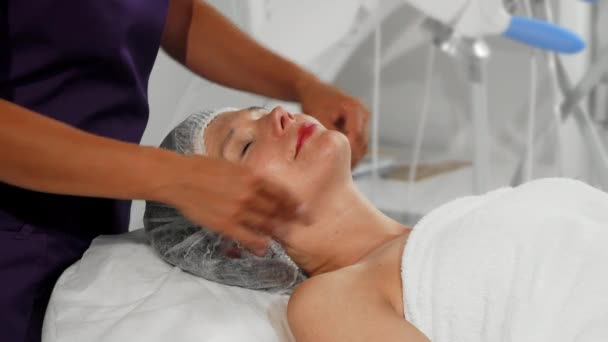 Feliz mujer mayor recibiendo masaje de cara y cuello en el spa — Vídeos de Stock