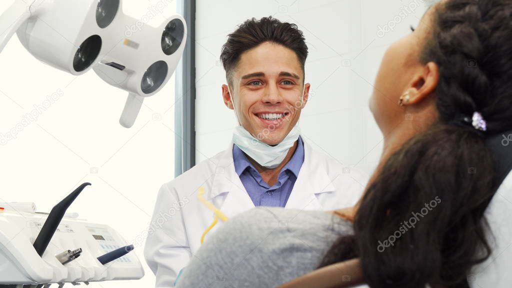 Handsome male dentist working with his patient