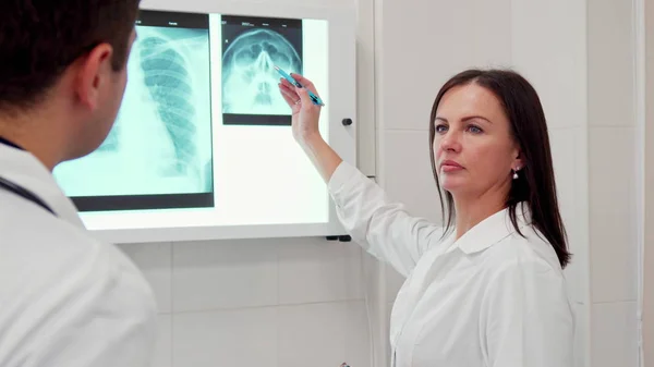 Female doctor points pencil on the x-ray of human head — Stock Photo, Image