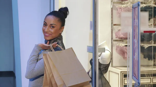 Mujer da la vuelta cerca de la ventana de la tienda con lencería —  Fotos de Stock