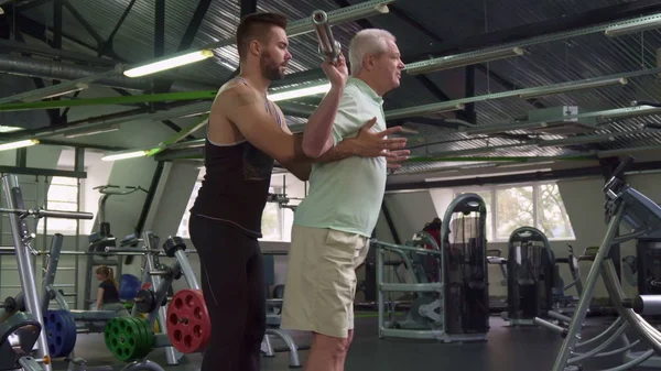 Trainer controls exercises of senior client