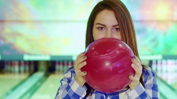 Girl looks out from behind the bowling ball — Stock Photo, Image