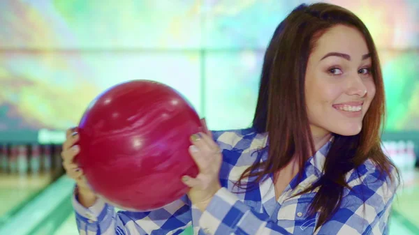 Girl holds bowling ball near her face — Stock Photo, Image