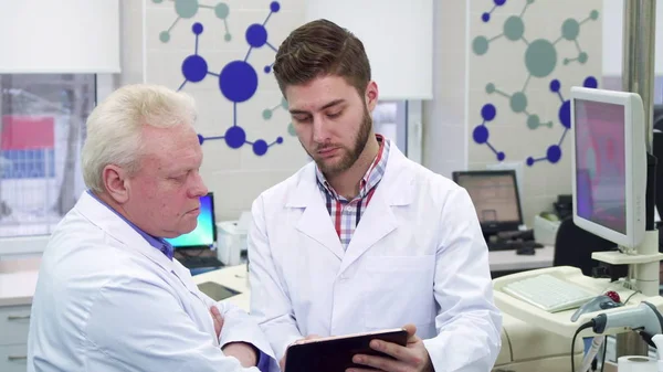 Homme scientifique montre quelque chose sur sa tablette à son collègue au laboratoire — Photo