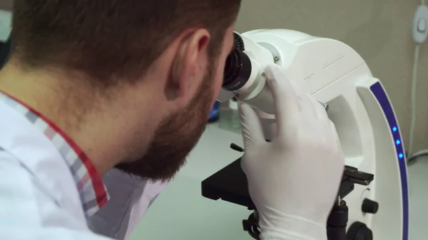 Man spins coarse adjustment knob on microscope at the laboratory — Stock Photo, Image