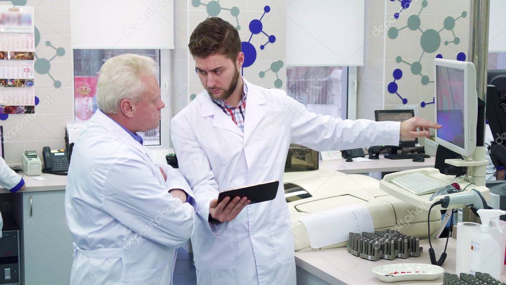 Man shows something on monitor to his colleague at the laboratory