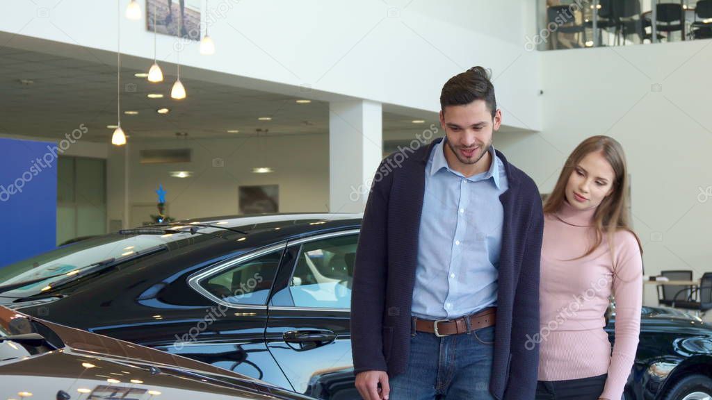 Young couple chooses car at the dealership