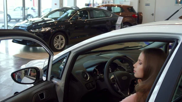 Frau setzt sich beim Autohaus ins Auto — Stockfoto