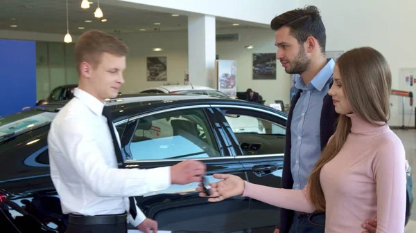 Verkäufer übergibt dem Paar den Autoschlüssel im Autohaus — Stockfoto