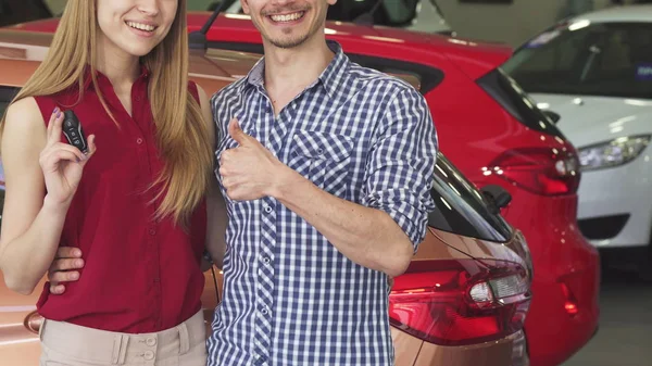 Schnappschuss eines lächelnden Ehepaares, das Autoschlüssel im Autohaus zeigt — Stockfoto