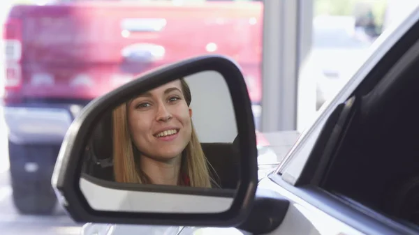 Belo motorista feminino sorrindo para a câmera no espelho lateral — Fotografia de Stock