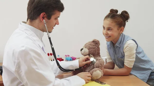 Uma menina levou seu ursinho de pelúcia para uma consulta médica . — Fotografia de Stock