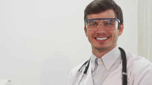 Seorang dokter tersenyum memakai kacamata laboratorium transparan khusus — Stok Foto
