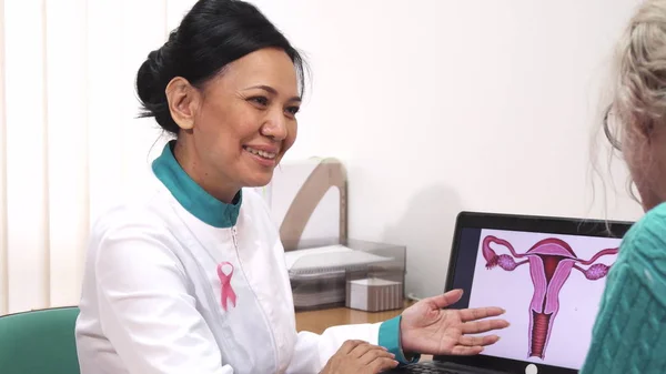 Female gynecologist talking to her patient showing uterus picture on the laptop — Stock Photo, Image