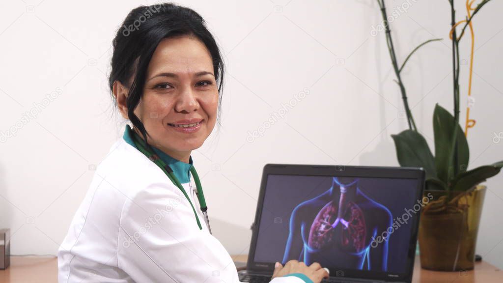 Mature female doctor examining lungs scan on her laptop at the clinic