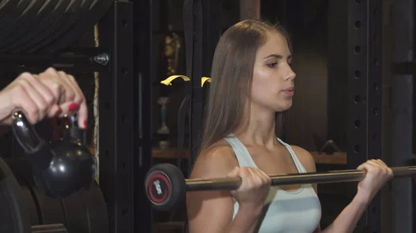 Beautiful sportswoman exercising with a barbell at the gym