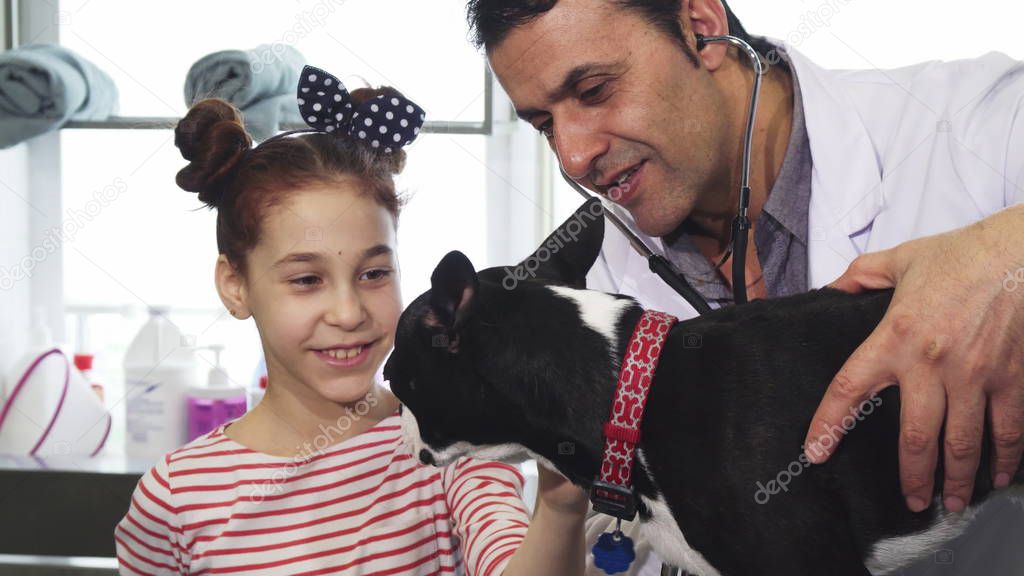 Cute little girl petting her dog during medical examination at the vet clinig