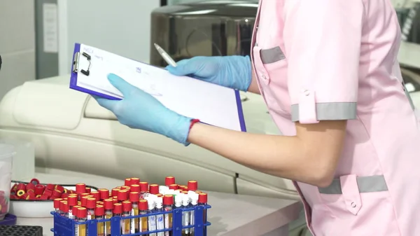 Cropped shot of a scientist taking notes while working with blood samples — Stock Photo, Image