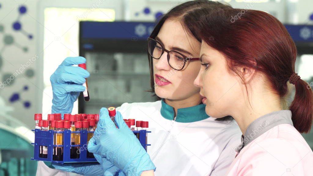 Two young female researchers working with blood test tubes