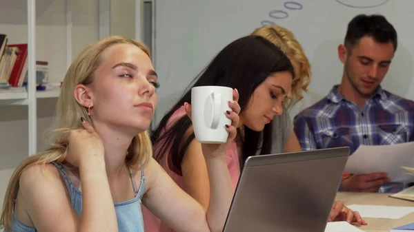 Jovem empresária parecendo cansada enquanto trabalhava com sua equipe — Fotografia de Stock