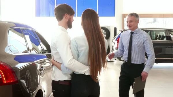 Verkäufer berät junges Paar im Autohaus — Stockfoto