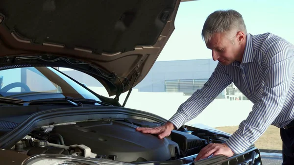 Reifer Mann schaut im Autohaus auf den Automotor — Stockfoto