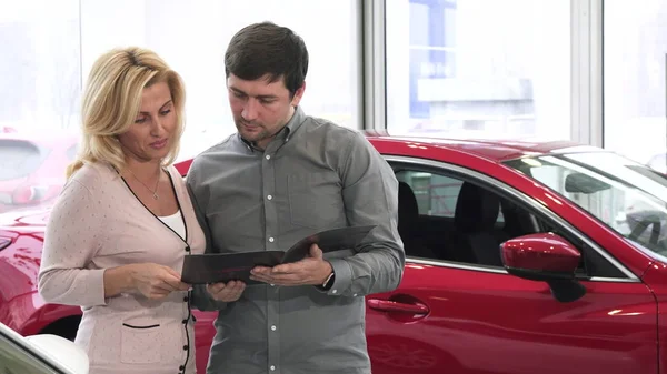 Ältere Paare lesen Broschüre im Autohaus und kaufen ein neues Auto — Stockfoto