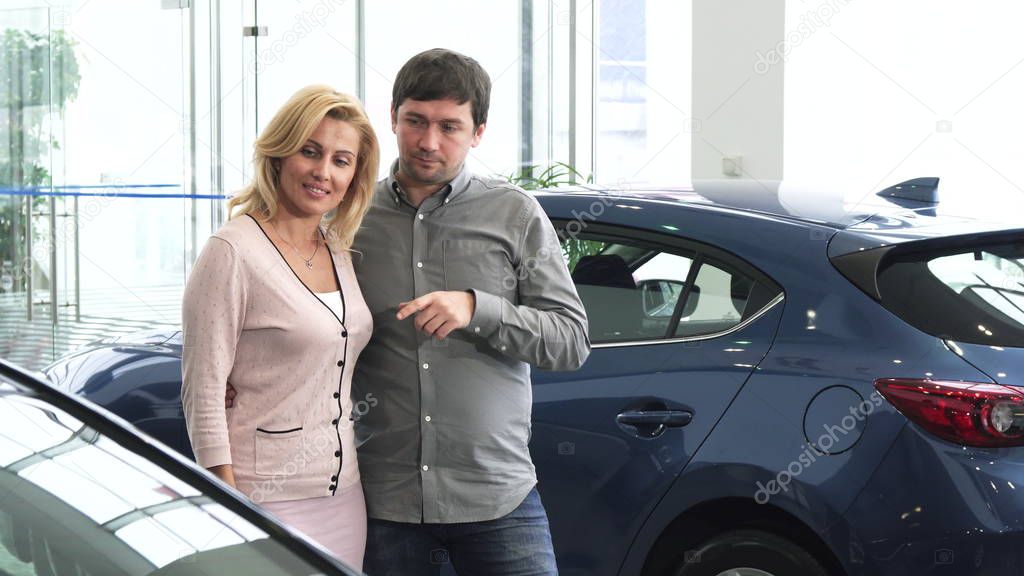 Mature couple choosing a new automobile at the dealership salon