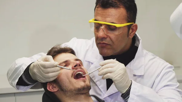 Close up de um dentista profissional examinando os dentes de seu paciente — Fotografia de Stock