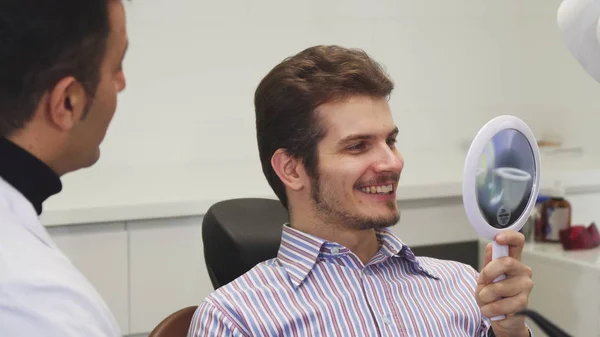 Pria muda yang bahagia melihat senyumnya yang sehat di kantor gigi — Stok Foto