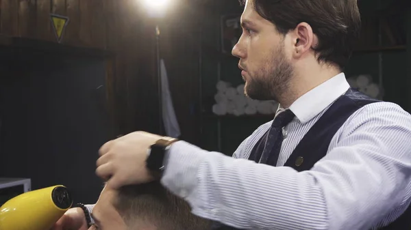 Профессиональный парикмахер высушивает волосы своего клиента — стоковое фото