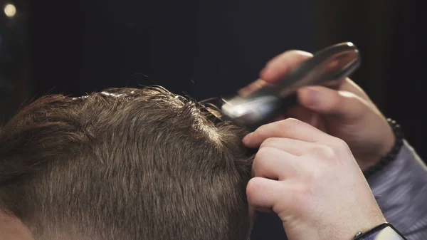 Обрезанный крупным планом парикмахера стригущего волосы своего клиента триммером — стоковое фото