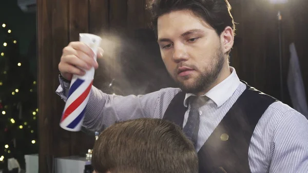 Профессиональный парикмахер распыляет волосы своего клиента во время укладки — стоковое фото