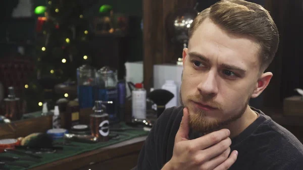 Knappe bebaarde man onderzoeken van zijn nieuwe kapsel op de barbershop — Stockfoto