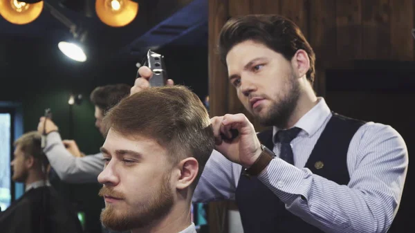 Barbier professionnel travaillant donnant une coupe de cheveux à son client — Photo