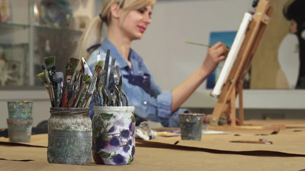 Foco seletivo em um monte de pincéis artista feminina trabalhando em sua pintura — Fotografia de Stock