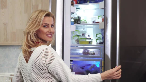 Buzdolabı mutfak at açılış kameraya gülümseyen güzel kadın